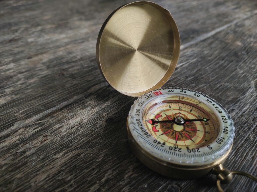 a compass on a wooden table with a gold case Photo by Ever Louie Pogosa